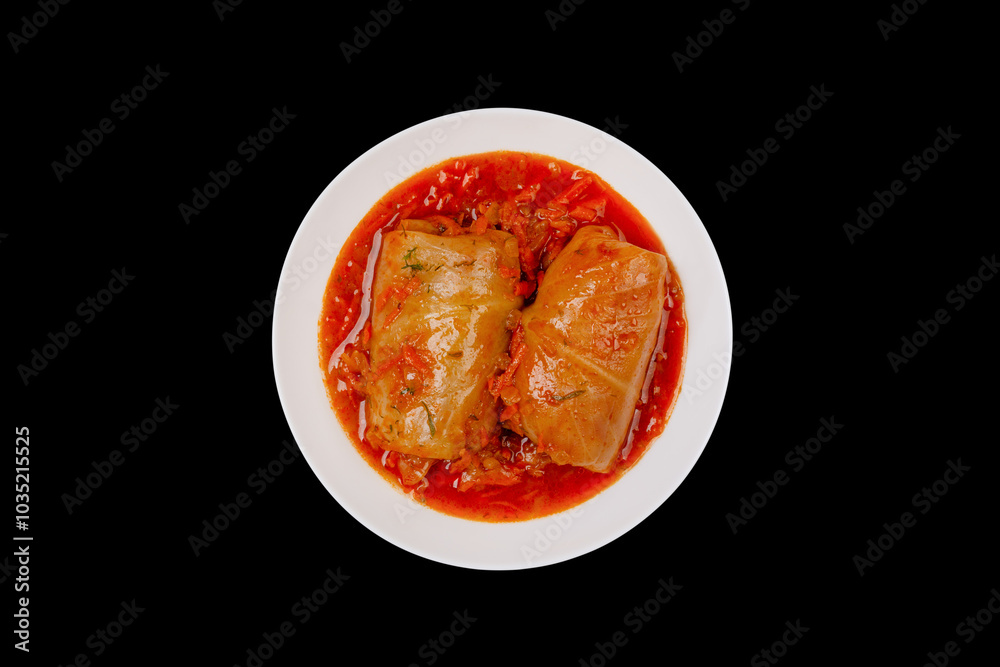 Two cabbage rolls stuffed with minced meat in vegetable gravy on a white platter isolated on black background top view Two cabbage rolls stuffed with minced meat in vegetable gravy on a white platter isolated on black background top view
