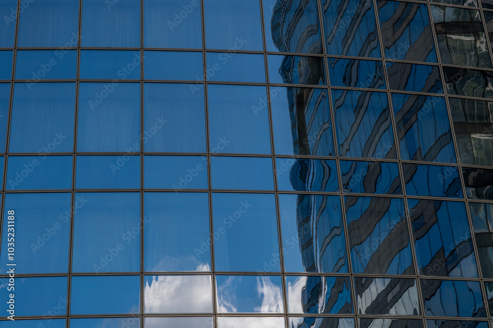 Windows of building at sunset. Reflection of the sky in the window glass. Skyscrapers in business district against blue sky. Looking up high-rise office buildings. Angled view.