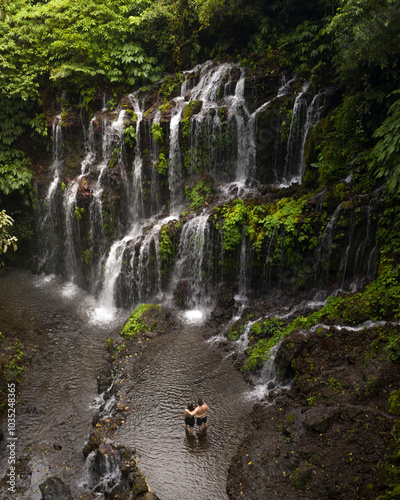 Aerial view of a breathtaking tropical waterfall surrounded by lush greenery and people, Bali, Indonesia. photo