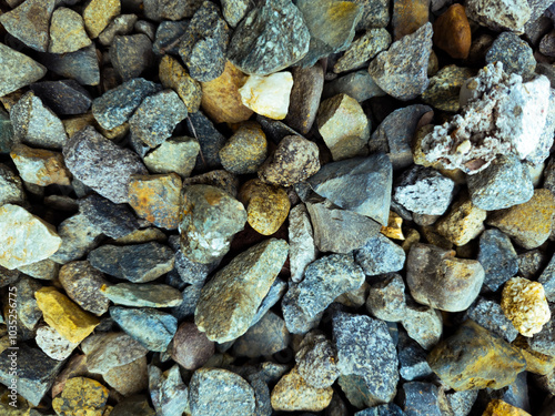 The photo shows a close-up of a collection of small, irregularly shaped rocks. The rocks are of various sizes and colors, including shades of gray, brown, and yellow. 