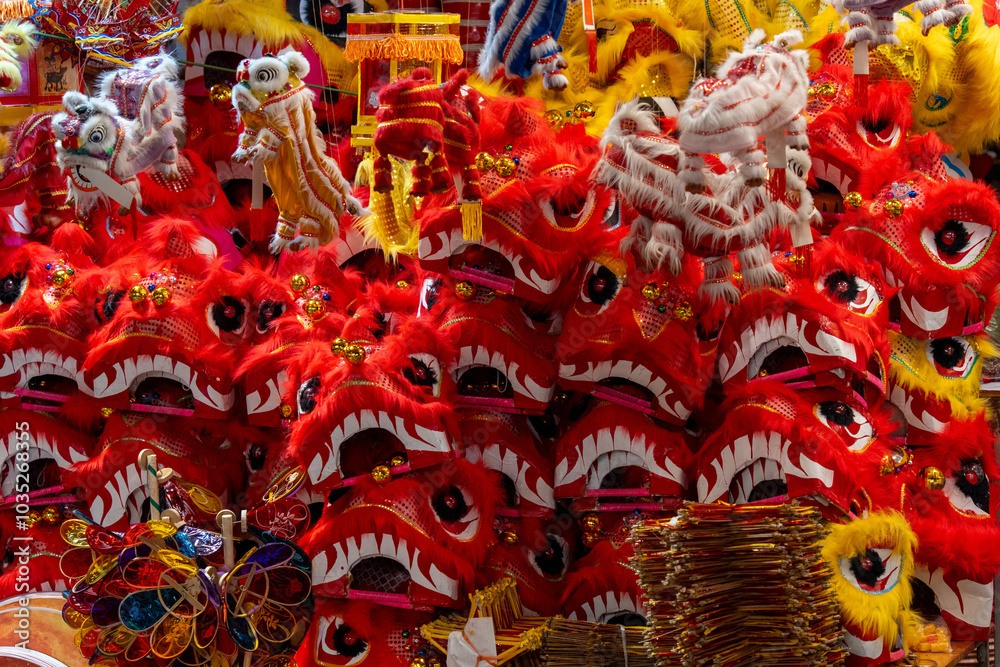 Fototapeta premium A close up shot of multiple red dragon masks with fur and decorative details. Colorful plastic toys and paper lanterns in the background