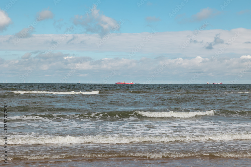 Waves at the beach, transport ships and offshore wind farm in the background. Waves at the beach, transport ships and offshore wind farm in the background.