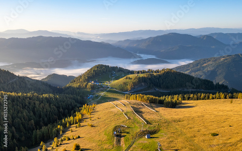 Aerial view of a tranquil valley with fog and sunrise over lush mountains, Aflenz, Austria. photo