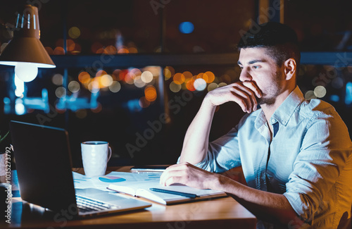 Thoughtful Office Manager At Laptop Working On Business Report Late At Night Sitting At Workpalce Indoors. Low Light photo