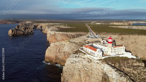 Golden aerial pulls back to reveal rock cliff at St Vincent lighthouse