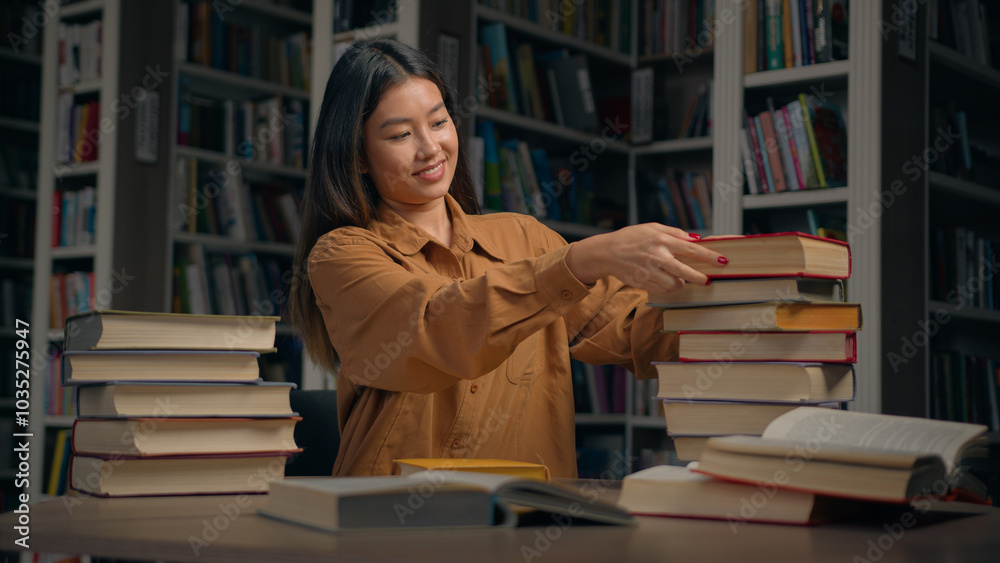 Asian woman girl student female library employee teacher bookworm reader sort books at desk near bookshelf preparing for exam at college university choosing book looking for textbook education concept Asian woman girl student female library employee teacher bookworm reader sort books at desk near bookshelf preparing for exam at college university choosing book looking for textbook education concept