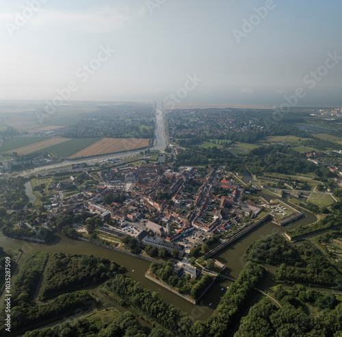 Aerial view of a historic fort city with beautiful architecture and greenery surrounding a river and fields, Gravelines, France. photo