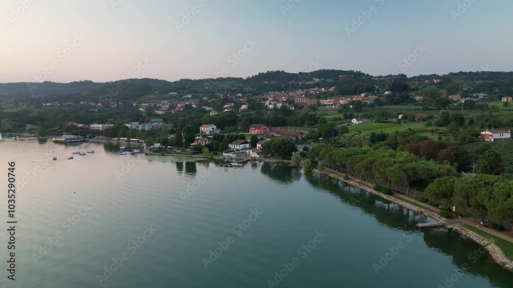 Aerial view of serene Lago di Viverone with picturesque village and tranquil shoreline surrounded by lush trees and hills, Viverone, Italy. Aerial view of serene Lago di Viverone with picturesque village and tranquil shoreline surrounded by lush trees and hills, Viverone, Italy.
