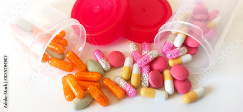 Pill capsules spill out of two plastic containers across a clean white surface to represent pharmaceutical distribution and healthcare management.