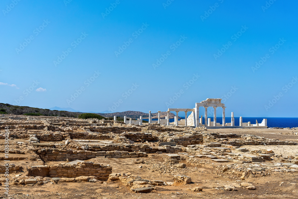 The ancient ruins of the sanctuary of Apollo at Despotiko Island, Greece, showcase magnificent marble columns and stone walls against the backdrop of the blue Aegean Sea.