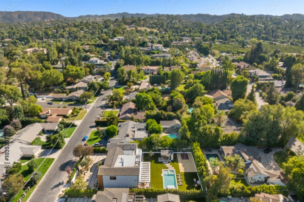 Obraz premium Aerial view of a suburban neighborhood with a modern house and pool.