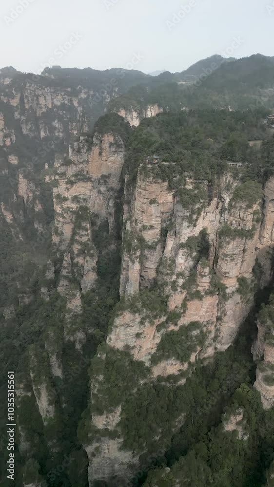 Aerial view of majestic mountains and cliffs with lush greenery in a serene valley, Zhangjiajie, China. Aerial view of majestic mountains and cliffs with lush greenery in a serene valley, Zhangjiajie, China.