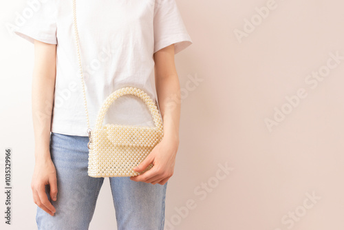 Foto Woman with a handmade bag made from pearl imitation beads over her shoulder in front of beige background