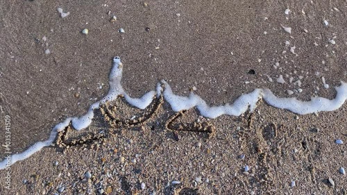 Year 2024 Written on Beach Sand with Wave Approaching