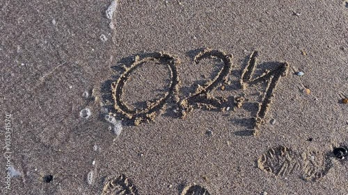 Year 2024 Written on Beach Sand with Wave Approaching