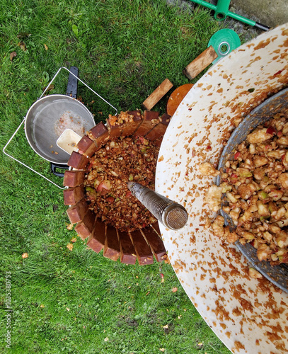 Making homemade cider juice from fallen apples pressing in a hand press with a screw children help to turn the handle cider flows out of the pulp through a sieve the pulp is thrown to the compost photo