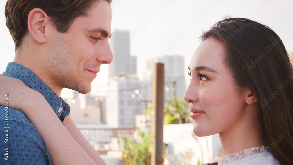 Portrait Of Romantic Couple Looking At Each Other On Rooftop Terrace With City Skyline In Background Portrait Of Romantic Couple Looking At Each Other On Rooftop Terrace With City Skyline In Background