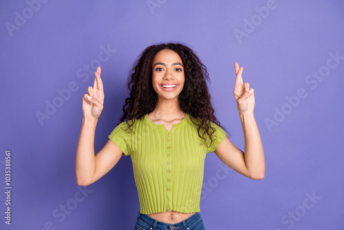 Photo portrait of pretty teen girl crossed fingers hope wear trendy green outfit isolated on purple color background photo