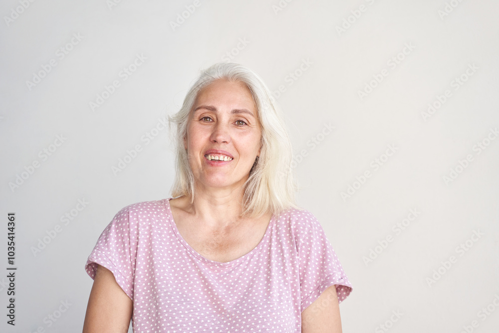Confident senior woman with white hair in casual polka dot shirt smiling against neutral background. Confident senior woman with white hair in casual polka dot shirt smiling against neutral background.