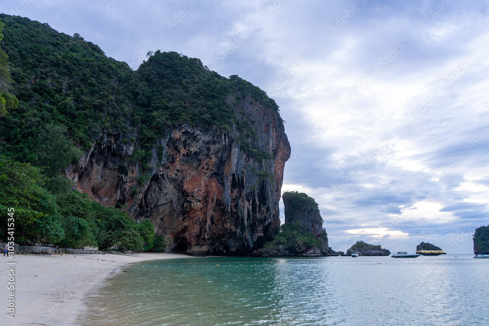 A serene beach with towering cliffs under a cloudy sky. A serene beach with towering cliffs under a cloudy sky.