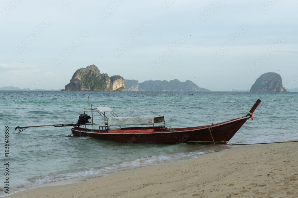 Longtail boat anchored on a serene beach with distant islands in the background. Longtail boat anchored on a serene beach with distant islands in the background.