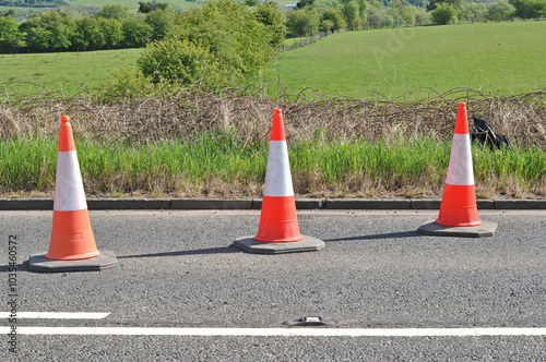 Three Orange Traffic Cones on Road Beside Farmers Field 