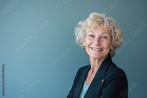 An older woman in a professional setting, smiling as she presents to a group, set against a solid color background, symbolizing her experience and authority photo