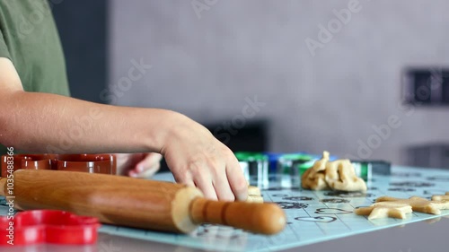 Close up of little boy hands making cookies using cookie cutters and dough in the kitchen at home