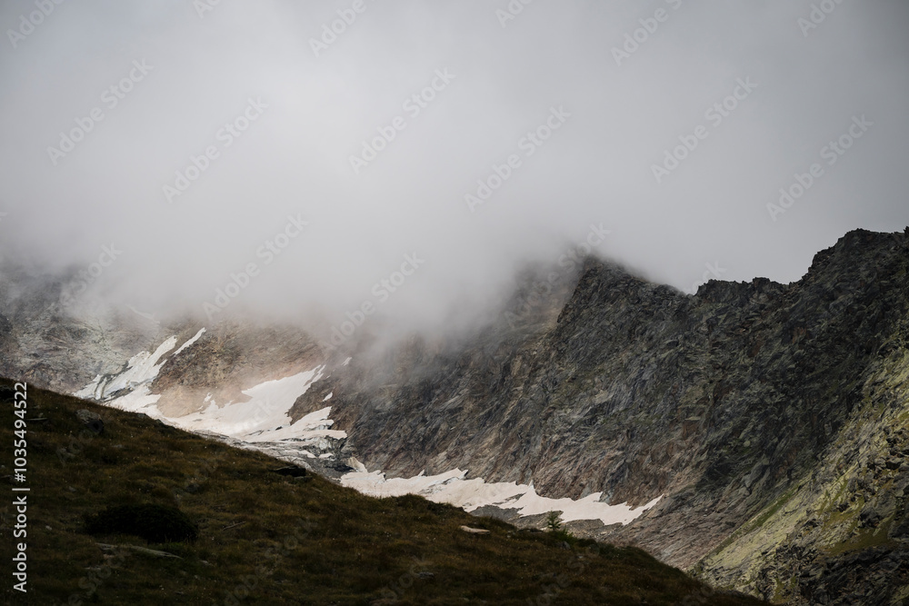 View of snowy peaks and rocky mountains under cloudy skies, Saas Fee, Switzerland. View of snowy peaks and rocky mountains under cloudy skies, Saas Fee, Switzerland.