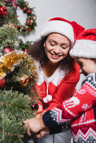 Selective focus of mother decorating Christmas tree with her daughter