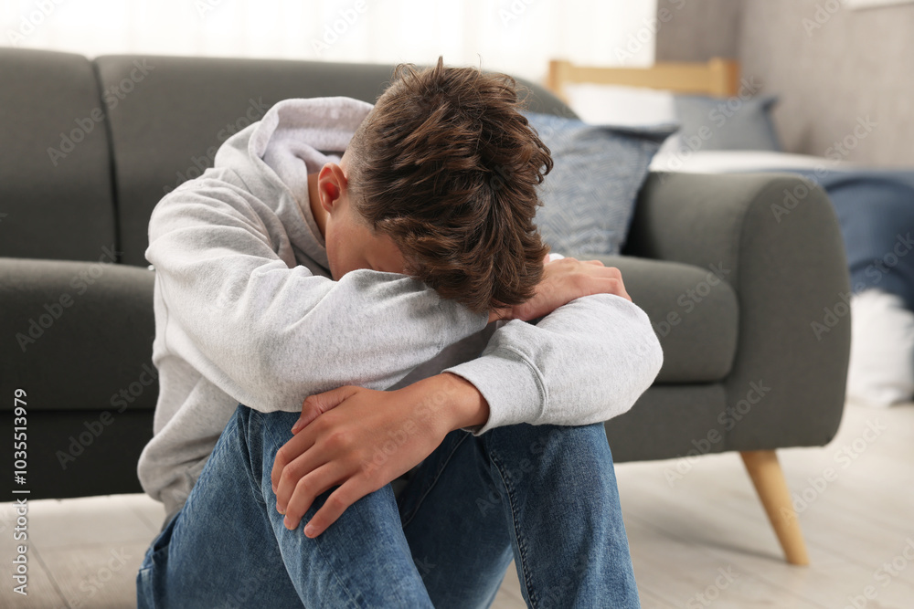 Loneliness concept. Sad teenage boy on floor at home Loneliness concept. Sad teenage boy on floor at home