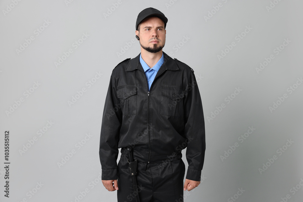 Security guard in uniform with earpiece on grey background Security guard in uniform with earpiece on grey background