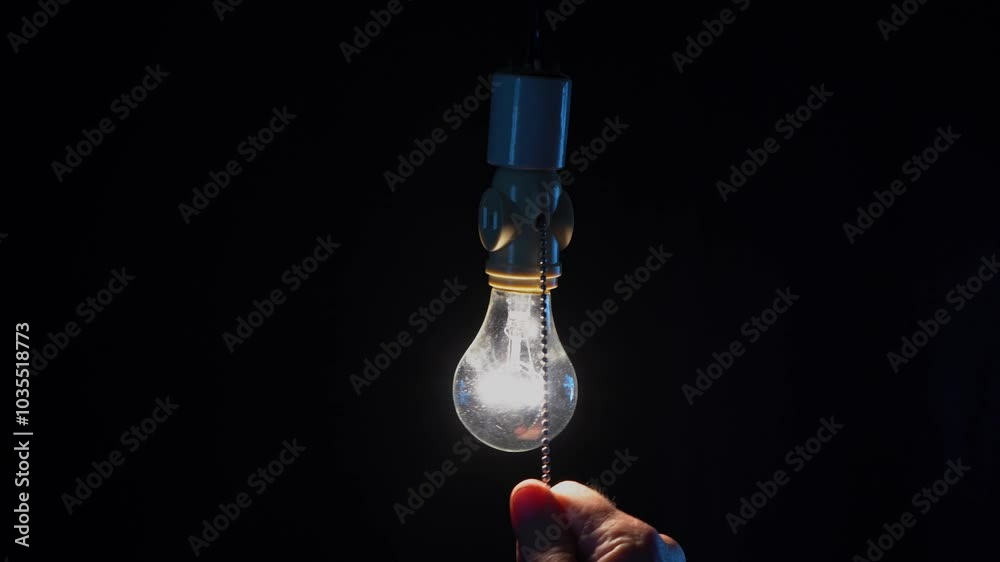 A man turning on a classic pull chain light