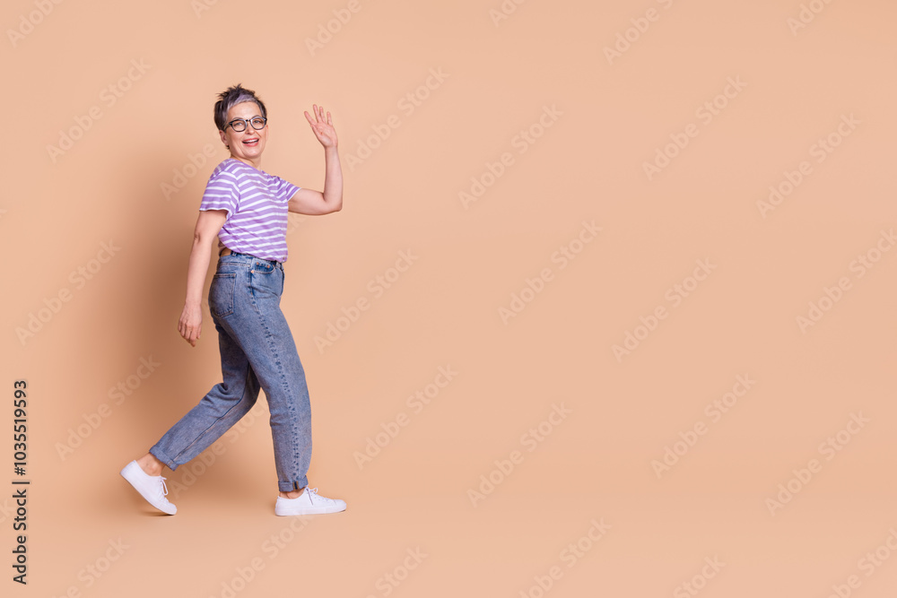 Photo of funny optimistic retired woman wear striped trendy clothes empty space isolated on beige color background Photo of funny optimistic retired woman wear striped trendy clothes empty space isolated on beige color background