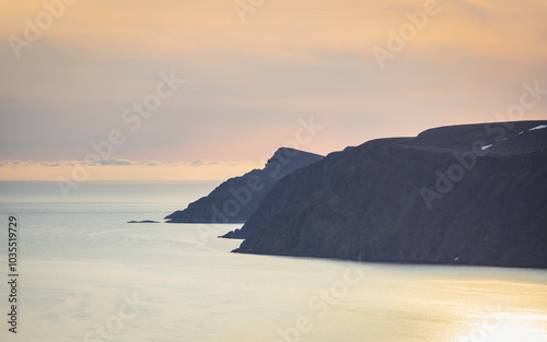 View of dramatic cliffs under a serene midnight sun over the Barents Sea, Honningsvag, Norway. photo