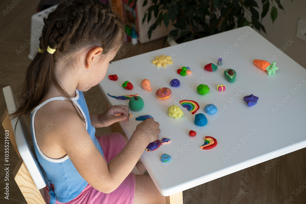 little girl is sitting at white wooden table and sculpting various figures out of airy plasticine, creative little girl is sitting at white wooden table and sculpting various figures out of airy plasticine, creative