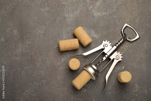 Wing corkscrew and corks on grey table, flat lay. Space for text photo