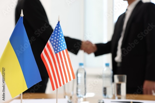Diplomats shaking hands during meeting indoors, focus on flags of USA and Ukraine photo