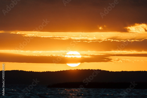 Epic sunset sky with big bright sun going behind the horizon in Lithuania. photo