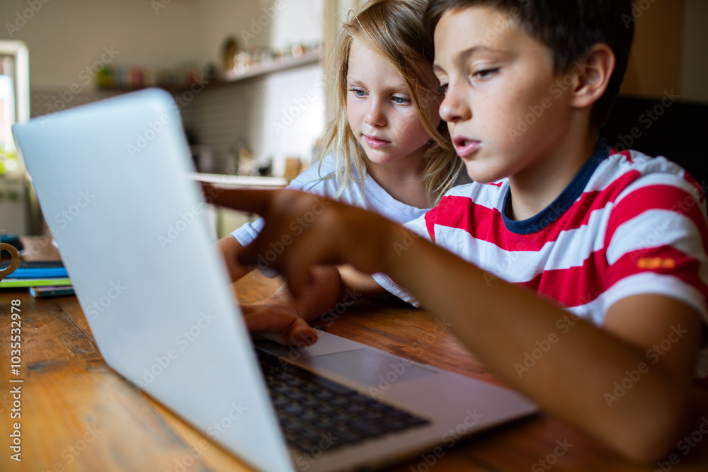 Kids focused on learning together with a laptop at home Kids focused on learning together with a laptop at home