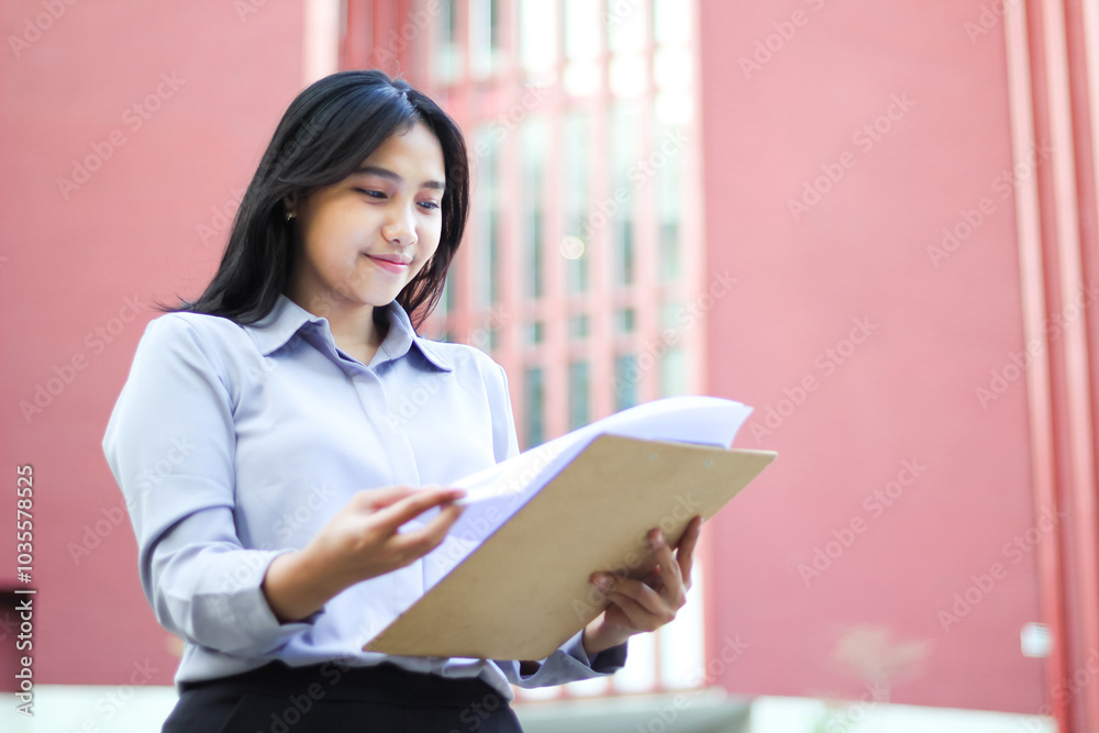 calm asian lawyer reading paperwork in outdoors wearing formal suit, peaceful female ceo holding report paper while walking over office building calm asian lawyer reading paperwork in outdoors wearing formal suit, peaceful female ceo holding report paper while walking over office building