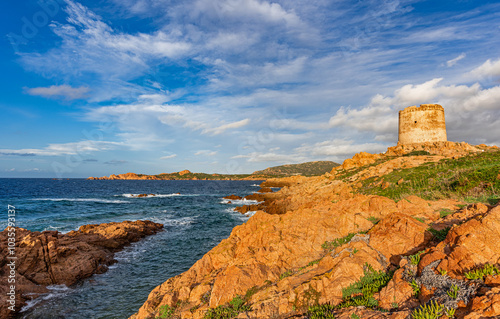 Fototapeta Naklejka Na Ścianę i Meble -  Red porphyry rocks and the historic tower of Isola Rossa at golden hour, municipality of Trinità d'Agultu and Vignola, Sardinia