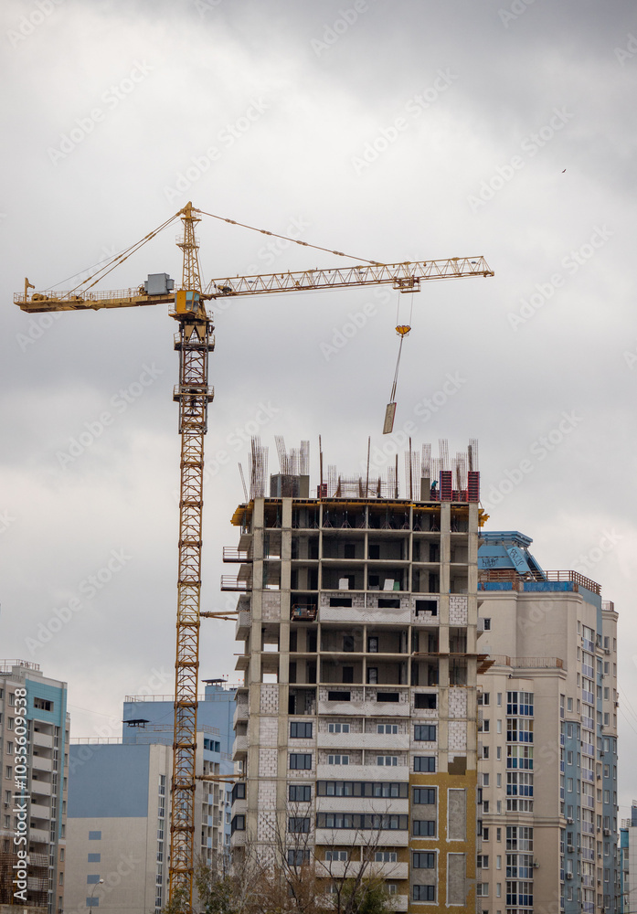 A crane is lifting a heavy object in front of a tall building A crane is lifting a heavy object in front of a tall building