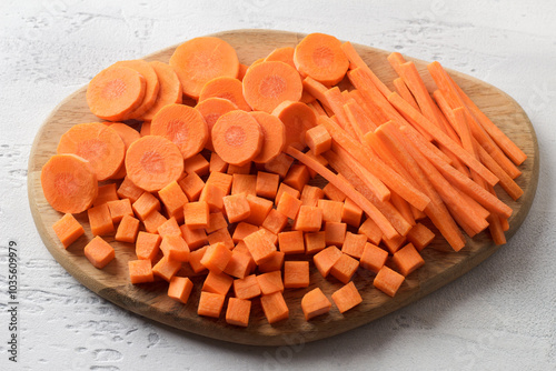 Cubes, bars, slices of fresh ripe carrots on a wooden board, three types of cutting vegetables. Healthy diet food