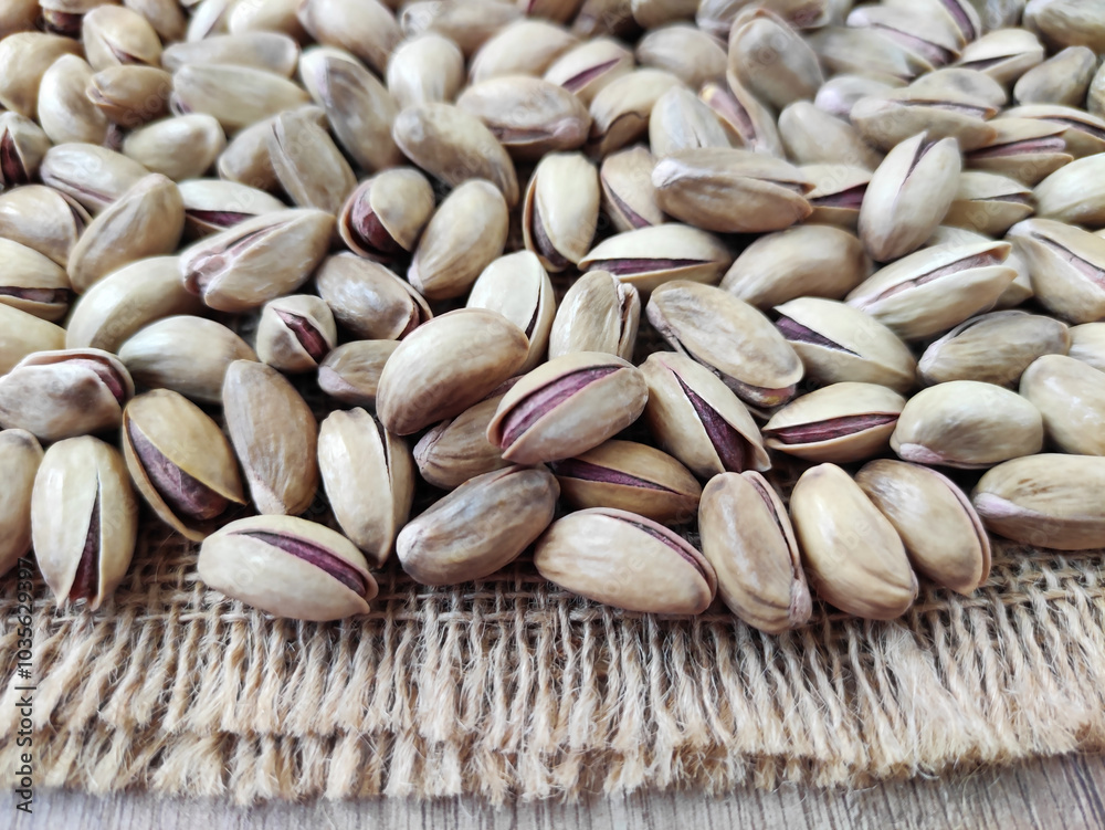 Fresh natural dried pistachios on woven jute fabric Fresh natural dried pistachios on woven jute fabric