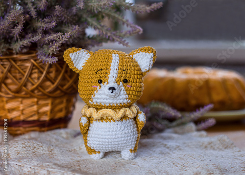 Soft toy crochet fox on the background of a basket with flowers and a pie, handmade toy miniature, selective focus