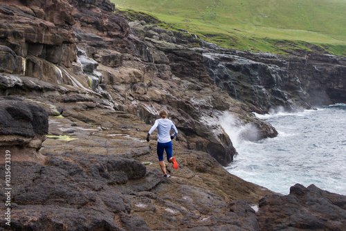 Women trail runner running on sea cliffs
