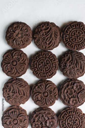 Overhead view of stamped chocolate cookies on a parchment lined baking tray, top view of embossed chocolate sugar cookies on a white background