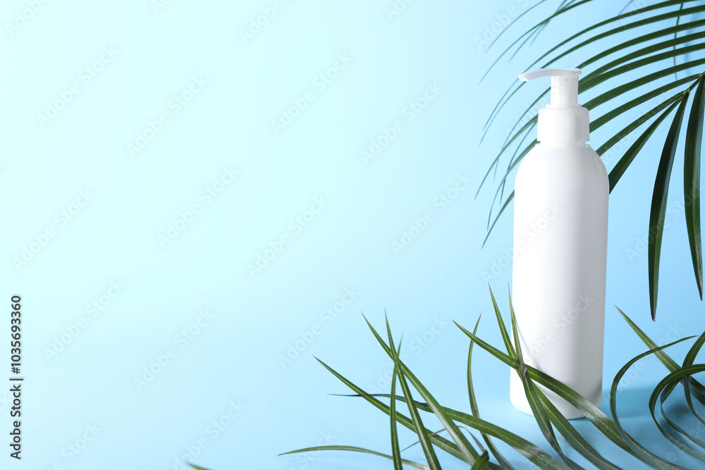 Shampoo in bottle and green palm leaves on light blue background. Space for text Shampoo in bottle and green palm leaves on light blue background. Space for text