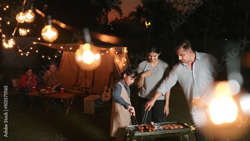 Family celebrate holiday in garden. Father, mother and child grill food for member. Outdoor camping activity to relax with meal and spend time with young generation cross generation gap. Divergence.